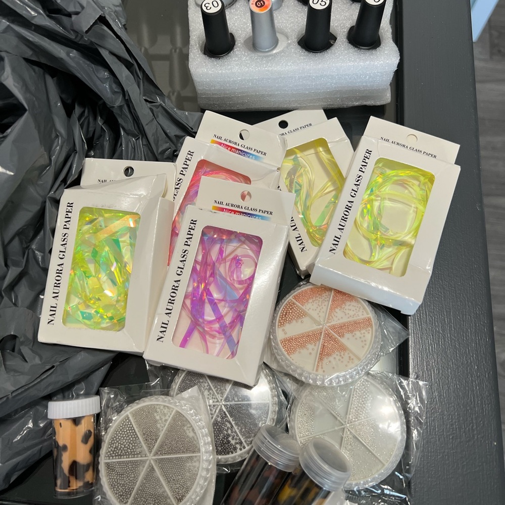 Assorted nail art supplies (aurora strips, caviar beads, gel polishes, foil)
